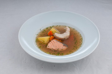 fish soup in atorsky serve from the chef on a white plate on a white background