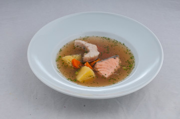 fish soup in atorsky serve from the chef on a white plate on a white background