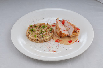 chicken with porridge in a beautiful atorsky serve from the chef on a white plate on a white background