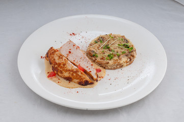 chicken with porridge in a beautiful atorsky serve from the chef on a white plate on a white background