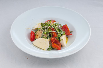 salad with cheese and grilled waxes on a white plate on a white background