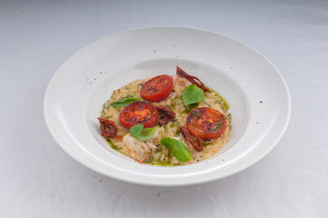 seafood risotto and dried tomatoes on a white plate on a white background