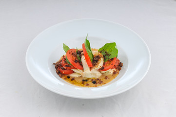 caprese salad on a white plate on a white background