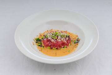 тартар из телятины на тыквеной подушке на белой тарелке на чистом белом фоне