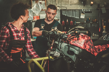 Mechanic and his helper repairing a motorcycle in a workshop