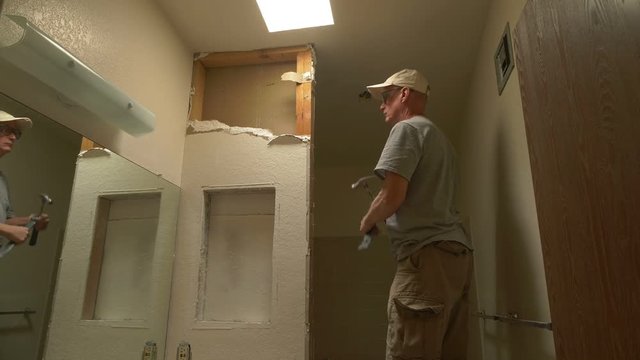 A carpenter tearing out a wall on a home remodel