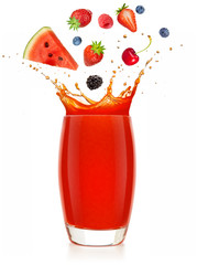 red fruits falling into a splashing glass of juice isolated on white background