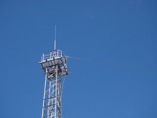 Fototapeta na wymiar Communication metal tower. Playground and spire on top. Background blue sky.