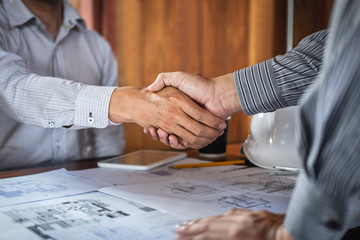 Handshake of collaboration, Construction engineering or architect discuss a blueprint and building model while checking information on sketching, meeting for architectural project of partner