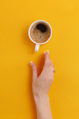 A cup of black coffee on a yellow background.