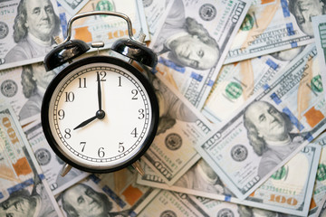 Alarm clock on a pile of US dollars banknotes background, Time to make money., business and saving money concept