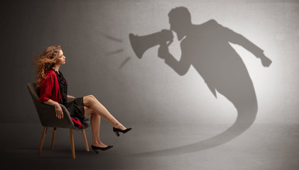 Dark shadow yelling with loudspeaker to elegant young lady
