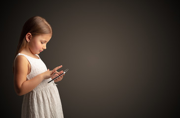 Adorable little girl using tablet with dark empty space
