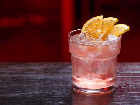 Closeup Of A Fitzgerald Cocktail In Short Glass, Gin, Standing On The Bar Counter, Isolated On A Red Light Background.