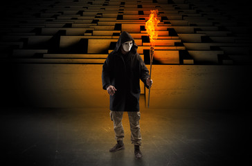 Ugly, aberrant man coming out from the labyrinth with burning flambeau on his hand
