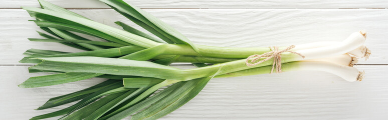 top view of fresh green leek on white wooden table, panoramic shot