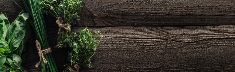top view of green onion, thyme and basil on wooden weathered table with copy space, panoramic shot
