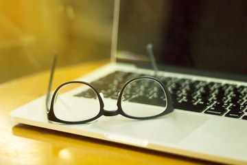 glasses and laptop on wooden desk. Lifestyle workspace.