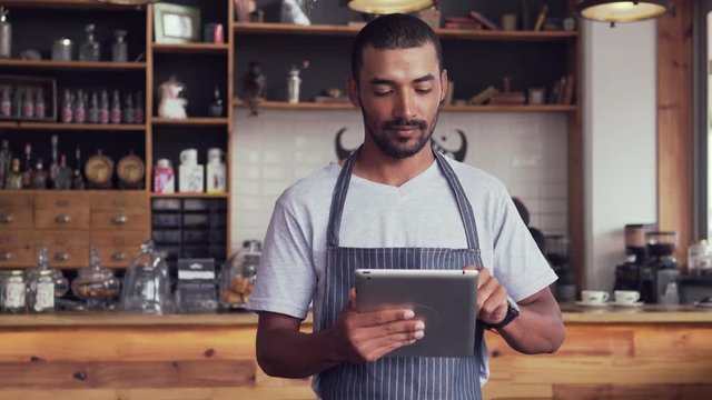 Male owner at his coffee shop using digital tablet