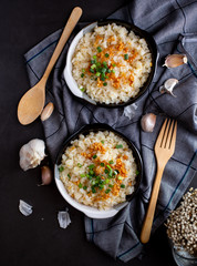 Garlic fried rice in ceramic plate with wood spoon on black background.