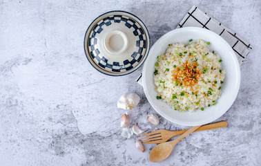 One white plate of garlic fired rice with spoon and soup bowl on white background.
