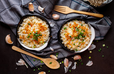 Garlic fried rice in ceramic plate with wood spoon on black background.