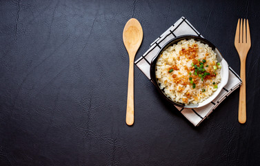 Garlic fried rice in ceramic plate with wood spoon on black background.