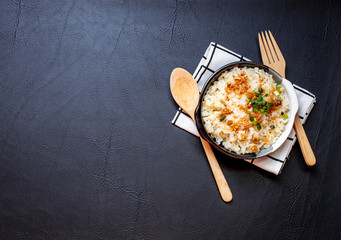 Garlic fried rice in ceramic plate with wood spoon on black background.