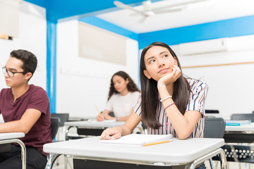 Cute Latin high school student daydreaming in class
