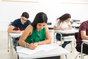 Focused Hispanic student answering an exam in a classroom