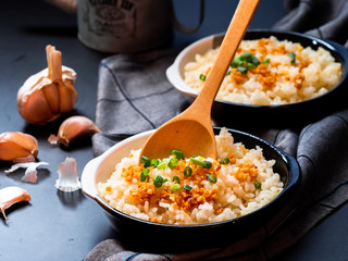 Garlic fried rice in ceramic plate with wood spoon on black background.