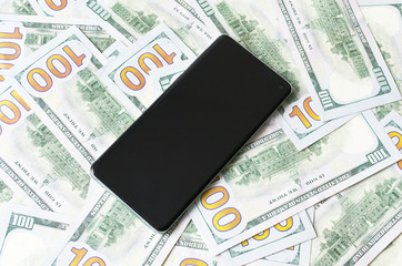 Mobile phone on the background of many hundred dollar banknotes 