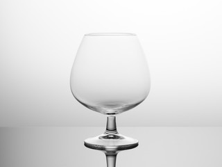 Glass empty wine glass on a glass surface. Backlight Black and white