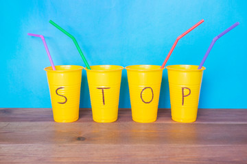 Disposable plastic tableware and word Stop on the blue background.