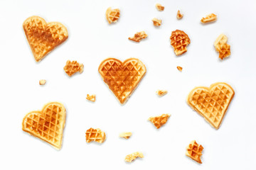 Background from Heart shaped waffles and pieces of waffle on white backdrop. Concept Love for Sweet