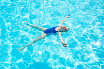 Happy little girl in goggles swim in swimming pool View from above Relax