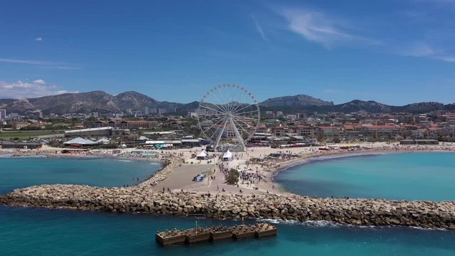 Aerial back traveling over Borely beach sunny day Marseille big wheel attraction mediterranean sea France