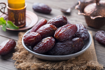 Fresh Medjool Dates in a bowl with tea. Ramadan kareem. Grey wooden background.