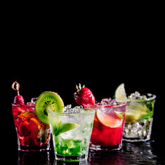 Four colorful tasty alcoholic cocktails in a row at the bar stand. Luxury vacation concept. Isolated on black