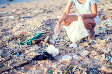 Woman collect garbage on the beach. Environmental pollution concept