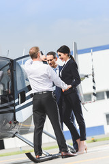 businesspeople in formal wear near helicopter and Pilot