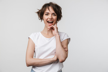 Image of attractive woman in basic t-shirt smiling at camera while standing with arms crossed