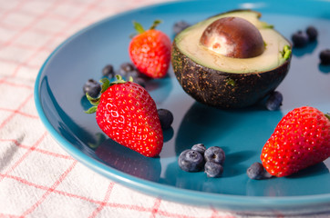 Avocado, strawberries and blueberries on plate