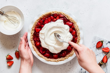 Female Spreading Cream Over a Strawberry Pie