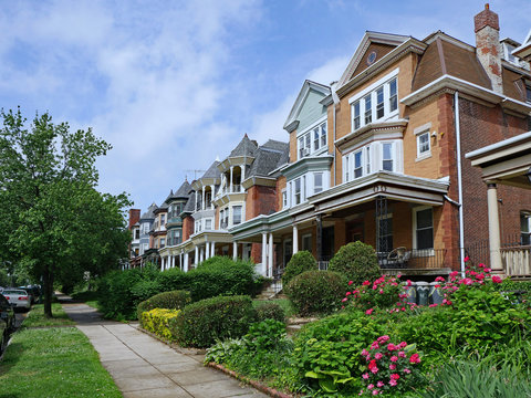 Row Of Large Old Brick Houses With Front Porches And Gardens