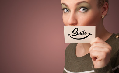 Person holding card with smile in front of her mouth
