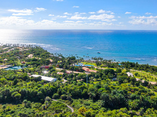 Fototapeta na wymiar Aerial view Praia do Forte, Bahia, Brazil. Beach and clear sea water with small waves and palm trees forest .Travel tropical concept