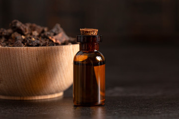 Bowl of Myrrh on a Dark Wood Table with a Bottle of Essential Oil