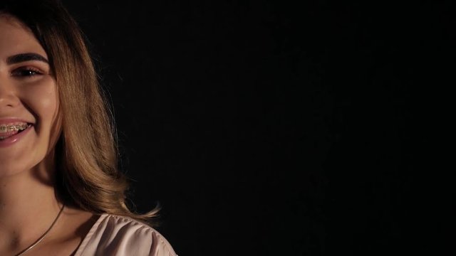 Sexy young girl model at the studio. Black background, blue spotlight, white blouse.