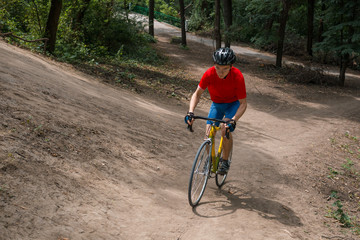 A cyclist rides on a road bicycle, going up hill.